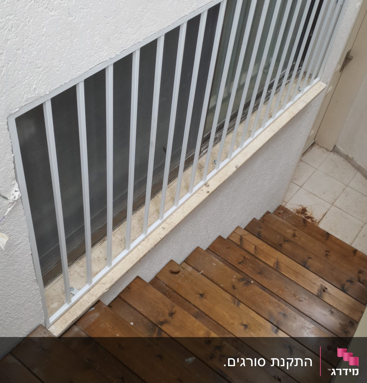 סורגי מתכת על חלון ליד מדרגות עץ